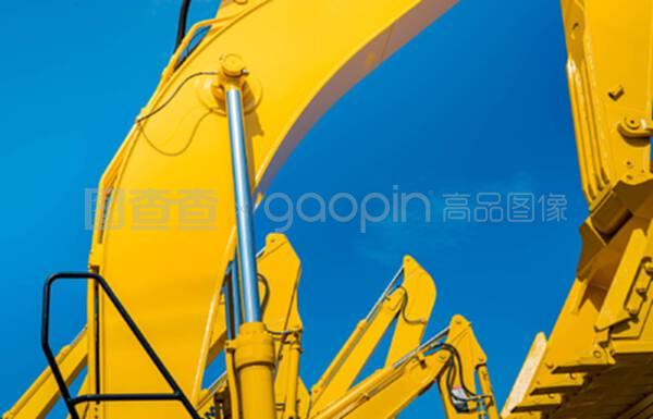 黄色挖土机,液压活塞臂,对抗晴朗的蓝天。建筑工地挖掘用重型机械。液压机械。大型推土机。重工业